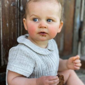 petite fille qui porte une barboteuse gris clair de la marque janne mill