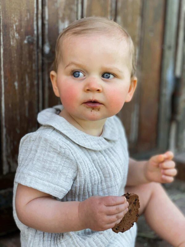 petite fille qui porte une barboteuse gris clair de la marque janne mill